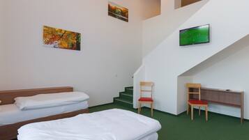 A hotel room with two beds, a TV mounted on the wall, a staircase, and a chair.