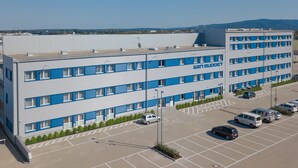 Un hotel moderno con tetto piatto, diversi piani e un parcheggio con numerose auto.