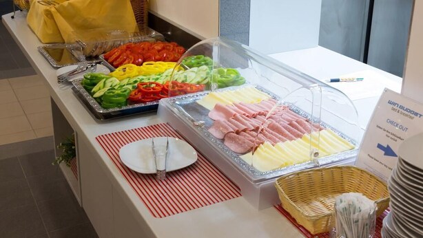 Un buffet con diverse pietanze, tra cui verdure e salumi a fette.