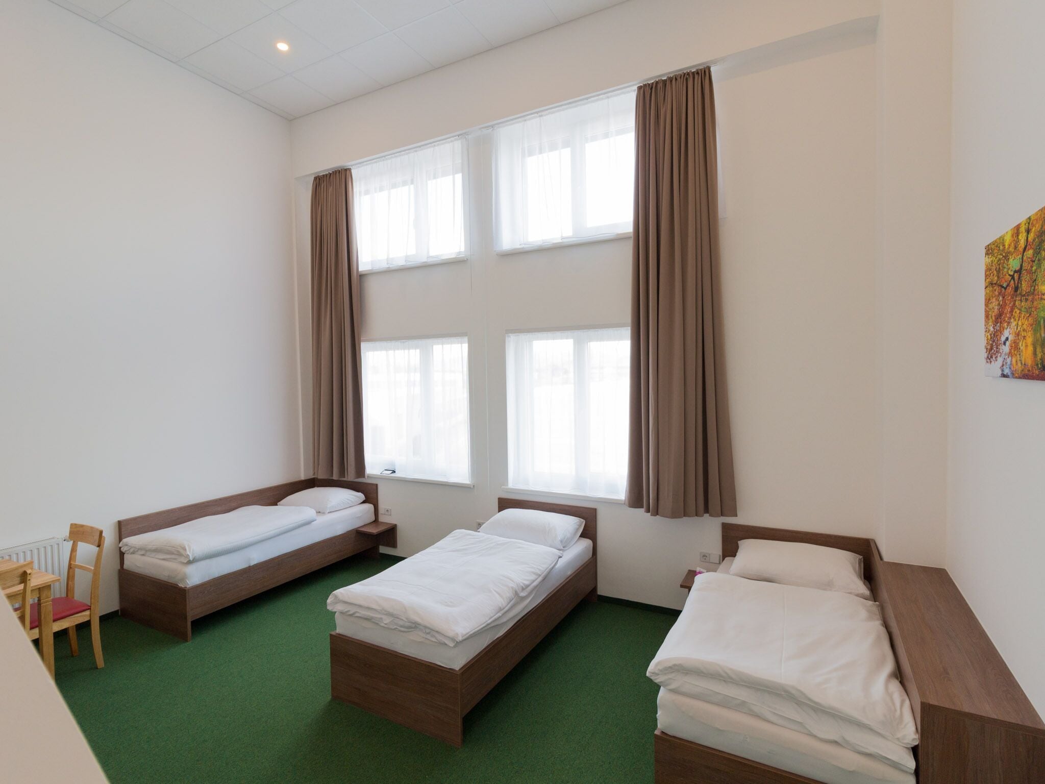 Une chambre avec trois lits simples, un bureau et une chaise.