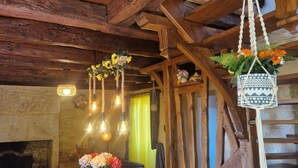 A rustic wooden interior with exposed beams, a wooden dining table with chairs, hanging light fixtures, and a hanging plant. - Maison Périgourdine Avec vue Magnifique, sur les Hauteurs de Sarlat (SARLAT LA CANEDA)