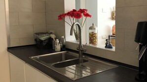 A modern kitchen with two stainless steel sinks, a black countertop, and a window with a view of the interior. - Beautiful 2-bedroom apartment in Tirrenia (Tuscany) (Marina di Pisa-tirrenia-calambr)