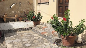 A stone-paved courtyard with potted plants and a wooden bench. - Beautiful 2-bedroom apartment in Tirrenia (Tuscany) (Marina di Pisa-tirrenia-calambr)