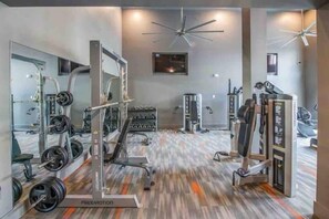 A gym with weightlifting equipment, cardio machines, and mirrors. - Sexy & Sensual 1BR Escape (Dallas)