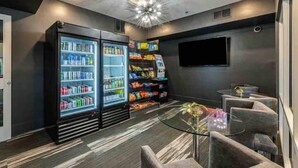 A modern lounge area with a seating arrangement, a large TV screen, and a vending machine. - Sexy & Sensual 1BR Escape (Dallas)