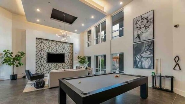 A modern living room with a pool table, a sofa, and a TV mounted on a geometric wall. - Sexy & Sensual 1BR Escape (Dallas)