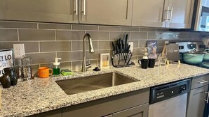 A kitchen with a granite countertop, stainless steel appliances, and a sign that reads "HELLO SWEET." - Sexy & Sensual 1BR Escape (Dallas)