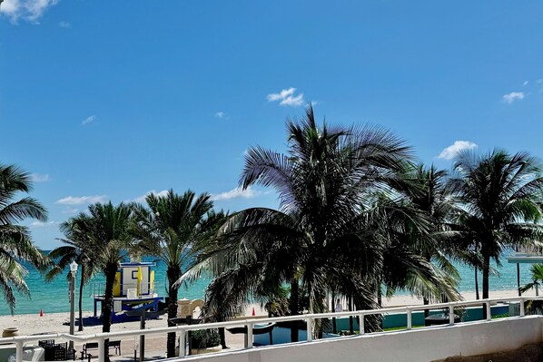 Une plage bordée de palmiers, une tour de surveillance pour les sauveteurs et un ciel bleu azur.