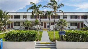 Un hotel de dos pisos con entrada central, palmeras y un letrero que indica 'Chateau Gardens' en la calle Lee número 311, Hollywood Beach.