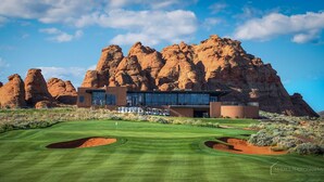 A modern building with a desert backdrop, featuring a well-maintained golf course in front.
