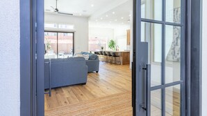 An open door to a modern living space with a grey sofa, wooden flooring, and a ceiling fan.