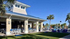 A building with a covered patio area, outdoor seating, and palm trees. - Luxurious Pool Home With Private Pool-2061lc 8 Bedroom Home by RedAwning (Davenport)