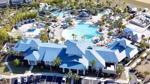 An aerial view of a resort with multiple swimming pools, a large building with a blue roof, and a beach in the background. - Luxurious Pool Home With Private Pool-2061lc 8 Bedroom Home by RedAwning (Davenport)