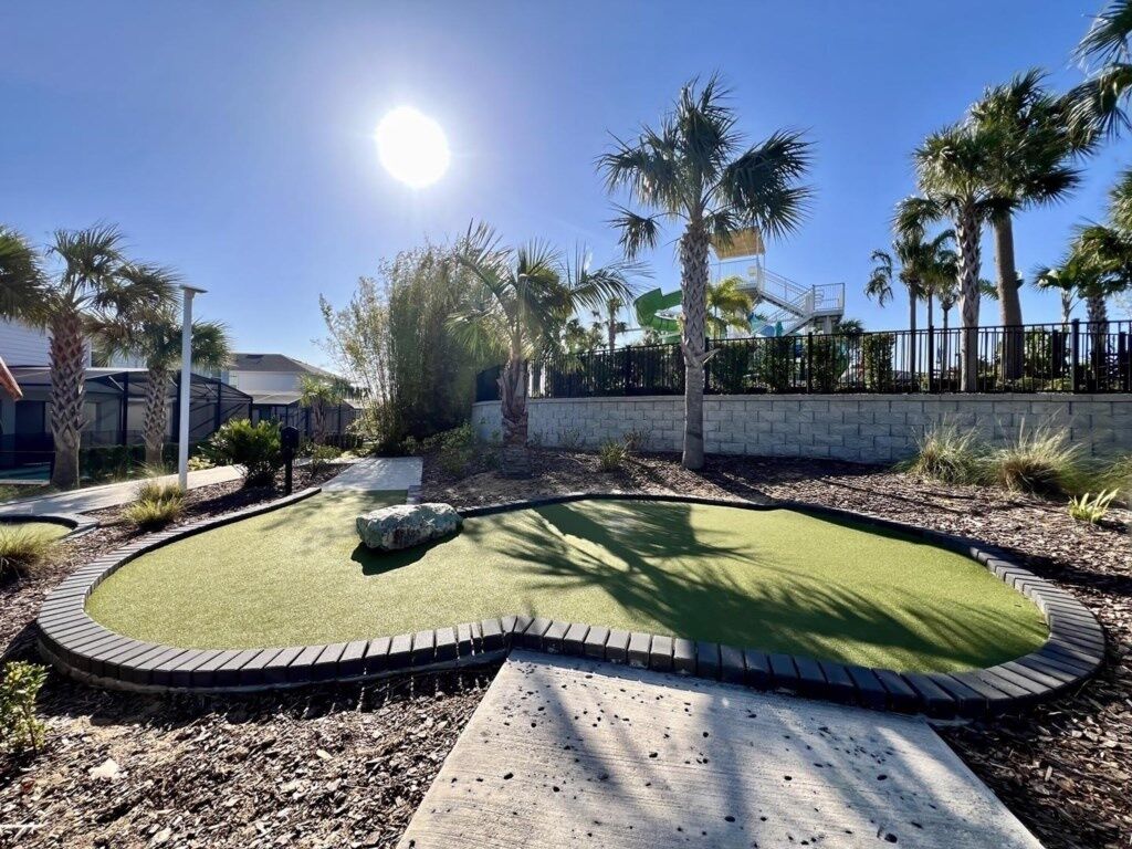 A landscaped area with a pool, palm trees, and a stone wall.