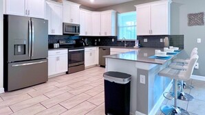 A modern kitchen with white cabinets, stainless steel appliances, and a central island with bar stools. - Spacious Home With Fun Decore And Game Room-4544tb 8 Bedroom Home by RedAwning (Kissimmee)