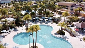Un resort con una amplia piscina, palmeras y varios edificios.