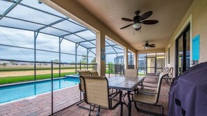 Eine überdachte Terrasse mit Pool, Sitzgelegenheit im Freien und Deckenventilator.