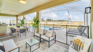 A covered outdoor patio with a pool, seating areas, and a view of the landscape. - 9 Bed Home With Theme Bedrooms Game Room,Pool Spa 9 Villa by RedAwning (Davenport)
