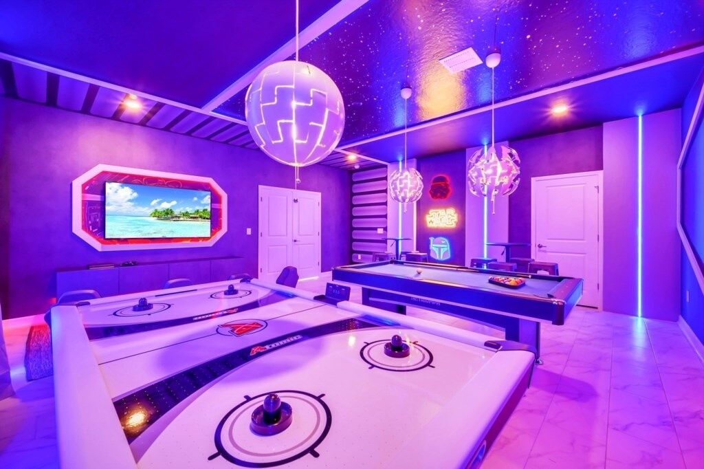 A pool table with a neon sign, a billiards table, and a neon-lit wall.