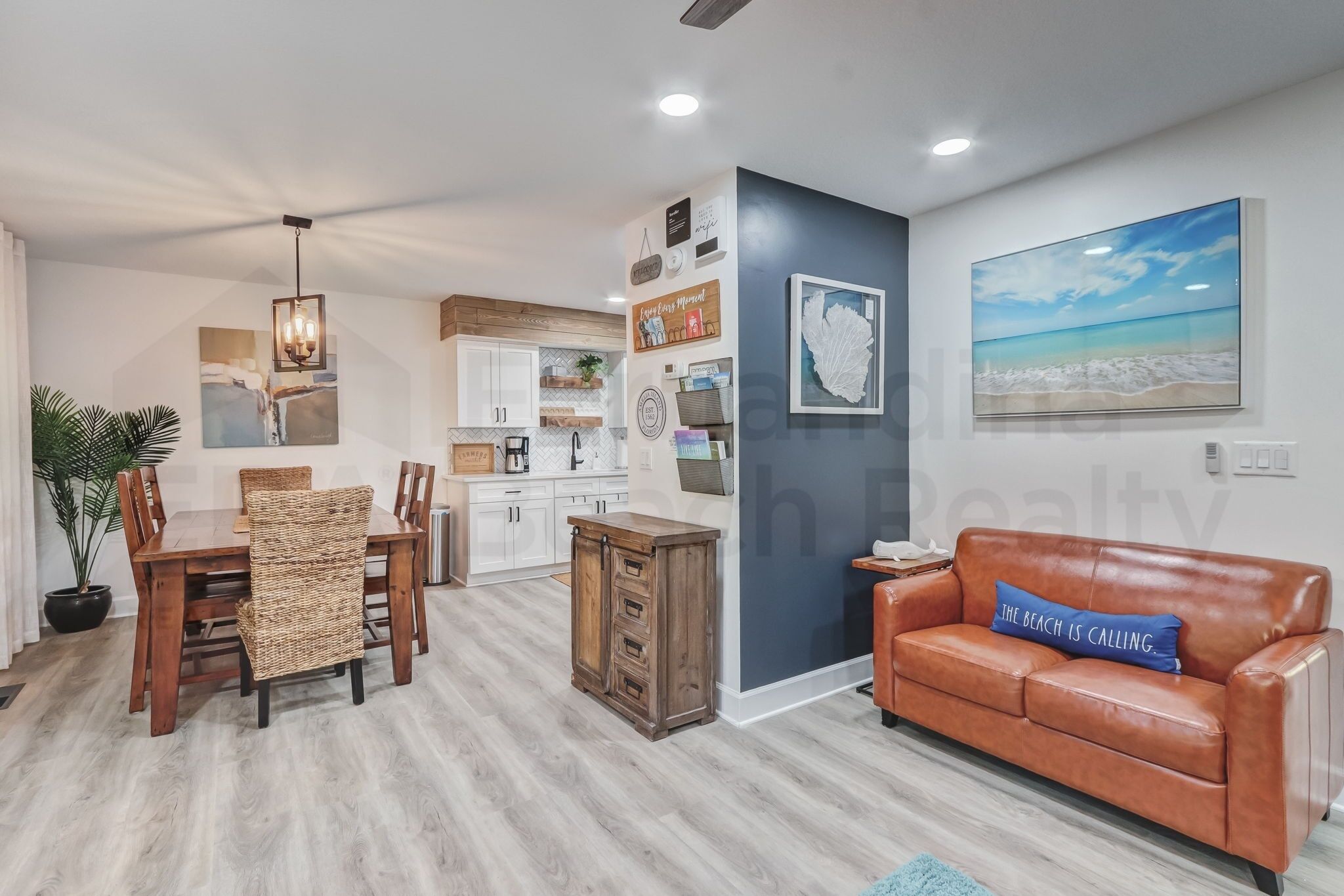 A modern living room with a dining area, a kitchen, and a large wall painting.