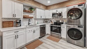 A modern kitchen with white cabinets, stainless steel appliances, and wooden accents.