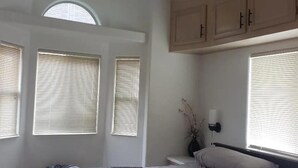 A bedroom with a bed, a ceiling fan, and three windows with blinds. - Odysea Modern Ocean Cabin 26 w/ Jacuzzi & Modern Decor (Private Beach Owned by White Rock Resort) (Smith River)