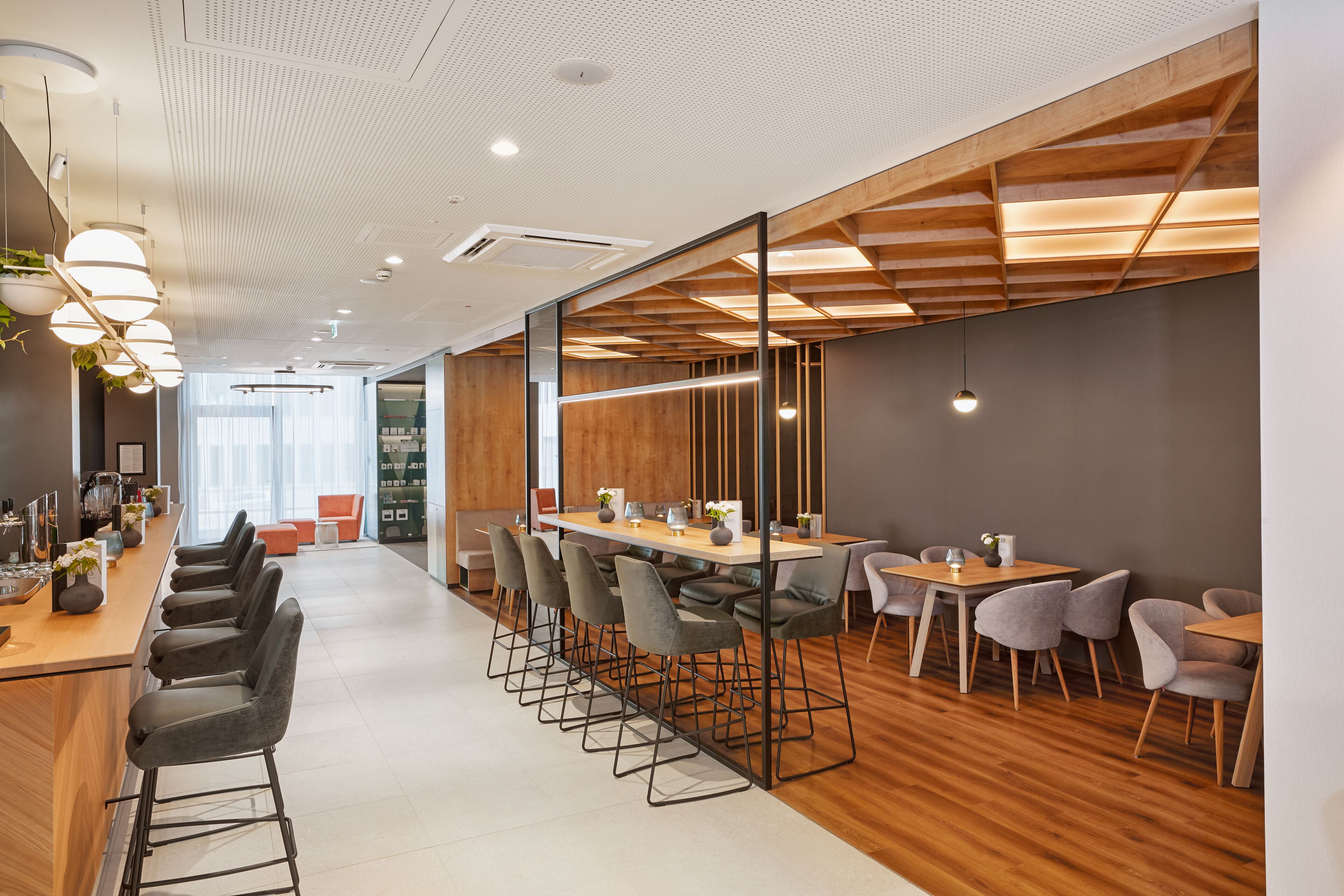 A modern office space with a long table, multiple chairs, and a bar area with stools.