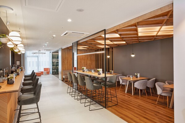 Un espacio de oficina moderno con una mesa larga, varias sillas y una zona de bar con taburetes.