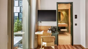 Habitación de hotel moderna con escritorio, silla y un amplio ventanal con vistas a la ciudad.