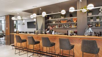 Zona bar moderna con un bancone in legno, sgabelli da bar e scaffali pieni di bottiglie.