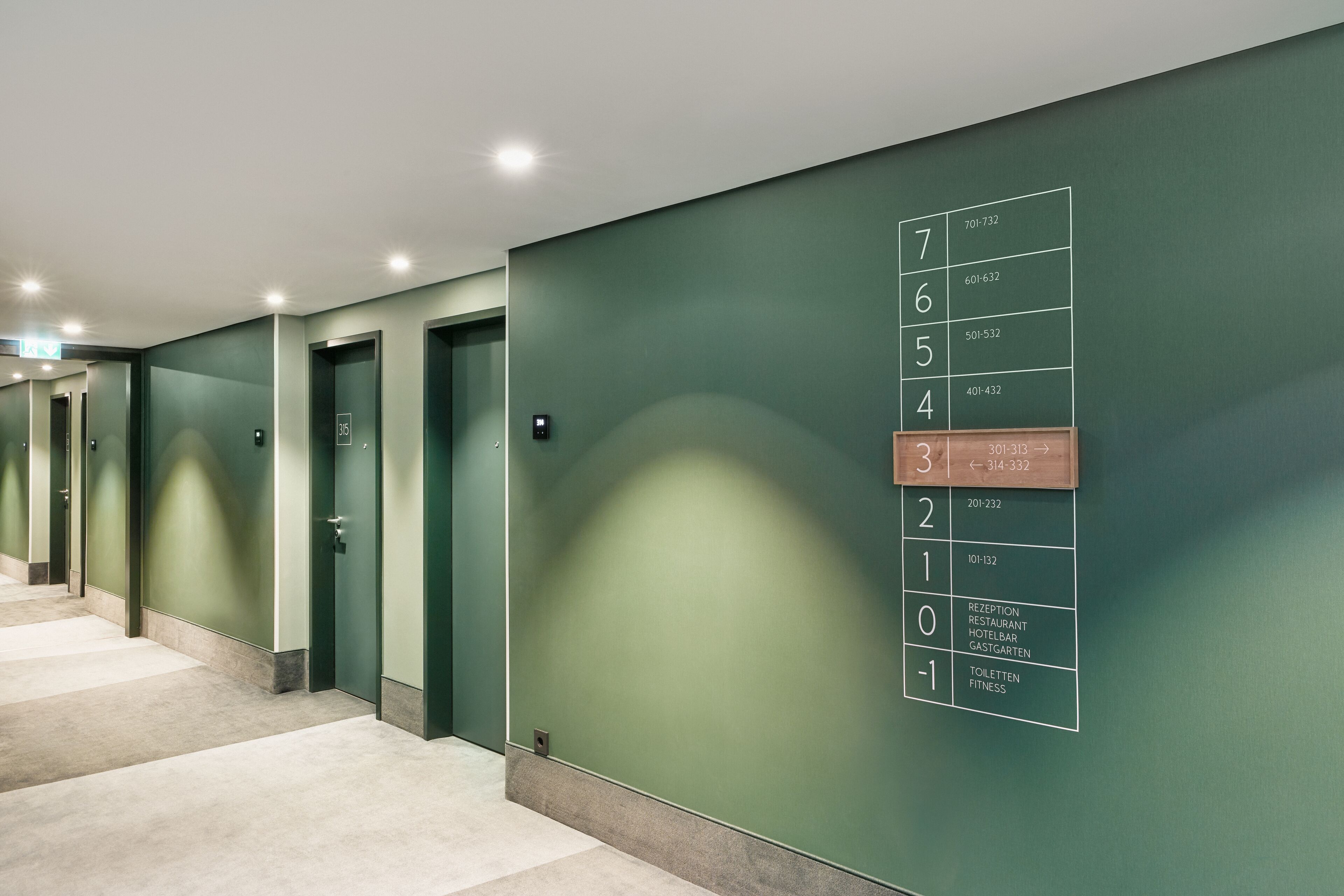 A hallway with numbered doors leading to various hotel rooms and amenities.