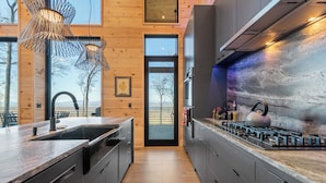 A modern kitchen with a large island, stainless steel appliances, and a view through the door. - Blue Ridge Ultra Luxury with Stunning Mountain & Lake Views, Near Aska & Marina (Blue Ridge)