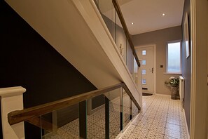 Una escalera con barandillas de vidrio que lleva a un rellano con una puerta y una ventana.