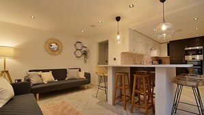 En moderne stue med sofa, sofabord og spiseplads med barstole.