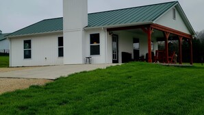 A white building with a green roof, a covered porch, and a chimney. - Lake Cabin near the Bourbeuse River (Leslie)