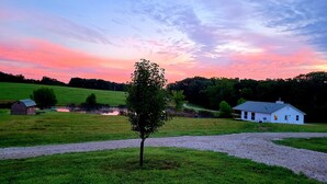 A rural landscape with a pond, a small tree, a barn, and a white house. - Lake Cabin near the Bourbeuse River (Leslie)