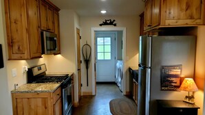 A kitchen with wooden cabinets, a stove, a microwave, a refrigerator, and a washing machine. - Lake Cabin near the Bourbeuse River (Leslie)