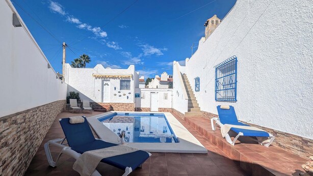 Un espace aménagé au bord de la piscine, comprenant une piscine, des chaises longues et un escalier menant à un bâtiment.