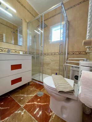 A bathroom with a glass-enclosed shower, a white toilet, a vanity with red handles, and a tiled floor. - Traditional Villa with Private Pool SM591 (San Miguel de Salinas)