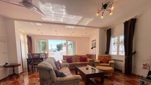 Un salon spacieux comprenant un grand canapé, une table basse et un coin repas avec une table et des chaises.