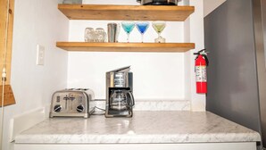 A compact kitchenette with a toaster, coffee maker, and a pot on a shelf. - Waters Edge Cottage (Merrimac)