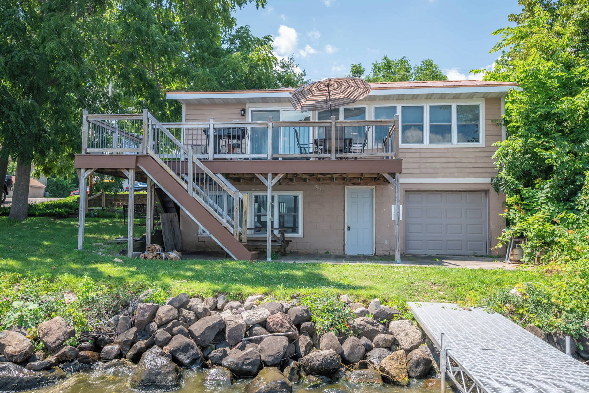 A two-story house with a deck, a garage, and a small pond.