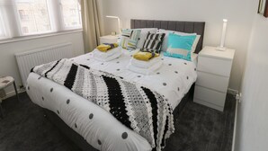 Une chambre bien rangée, avec un lit, des tables de chevet et une fenêtre avec des rideaux.