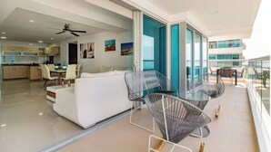 Ein modernes Wohnzimmer mit einer Couch, Sesseln und einem Balkon mit Aussicht.