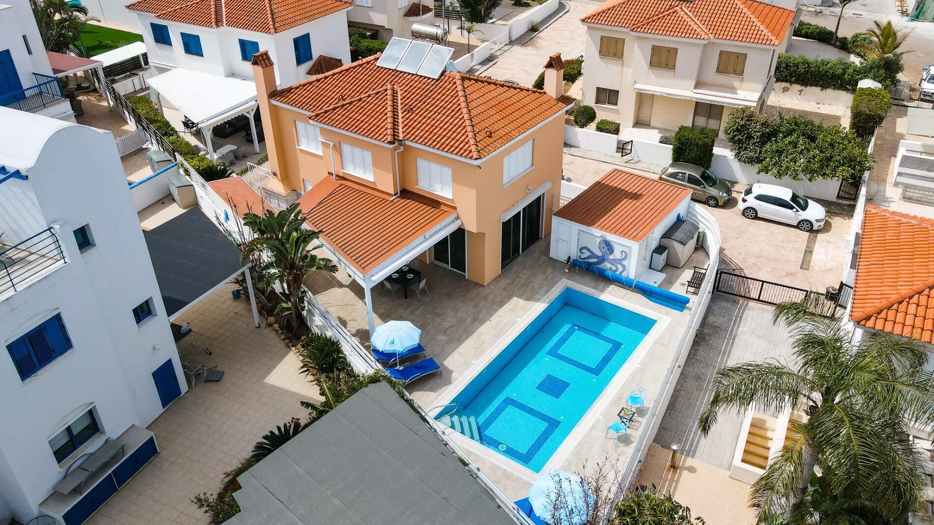 En boligbygning med swimmingpool, solpaneler og en overdækket patio.