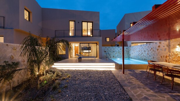 A modern house with a swimming pool, outdoor seating, and a well-lit entrance. - Nisi Living Concept - Rhodes Villa (Ialysos)