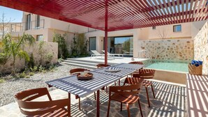 An outdoor patio with a table and chairs, a pool, and a covered area with a red roof. - Nisi Living Concept - Rhodes Villa (Ialysos)
