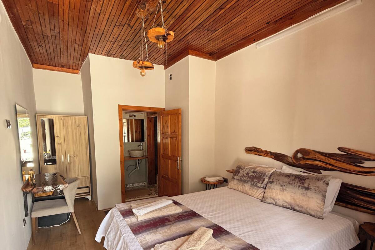 Ein Schlafzimmer mit Holzboden, einem Bett mit gemustertem Überwurf, einem Holz-Kopfschild und einem kleinen Nachttisch.