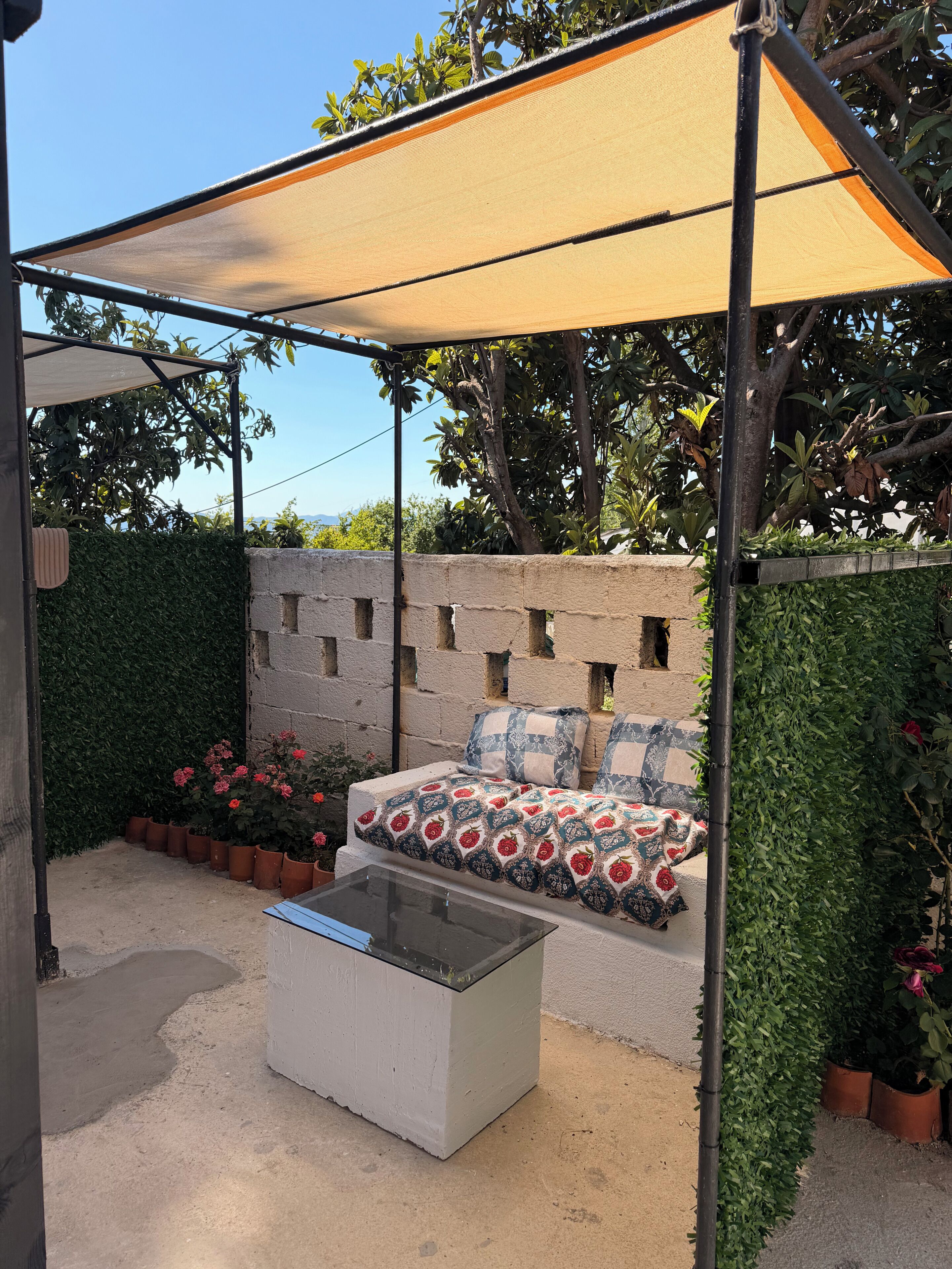 An outdoor seating area with a sofa and cushions, a table, and a canopy.