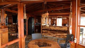 A rustic wooden interior with a large round table, wooden walls, and a hanging light fixture.